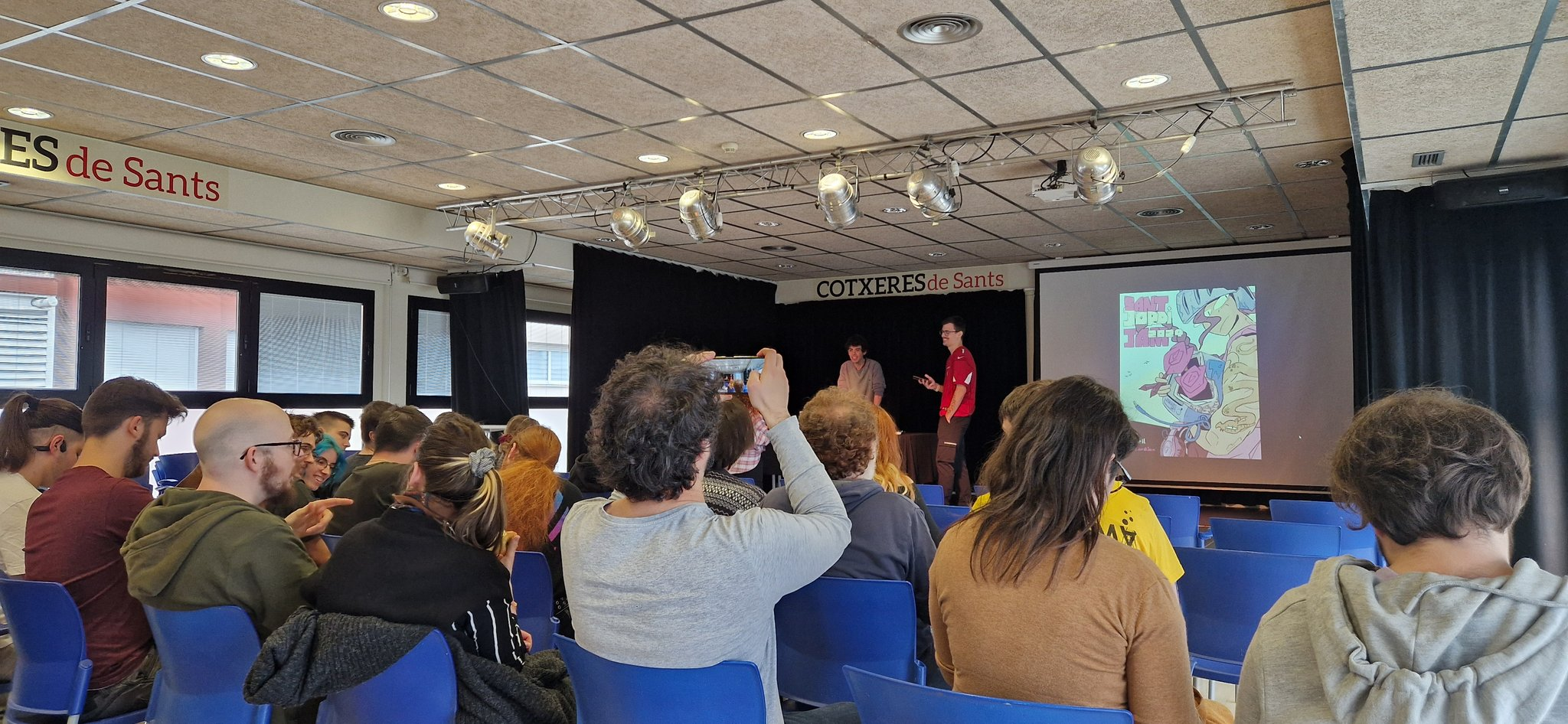 Foto de la Sant Jordi Jam on es poden veure a Paco Juan i a Víctor en l'escenari, presentant l'esdeveniment. Ely i jo estem a la dreta del tot, no se'ns veuen les cares perquè la foto està feta des de darrere.